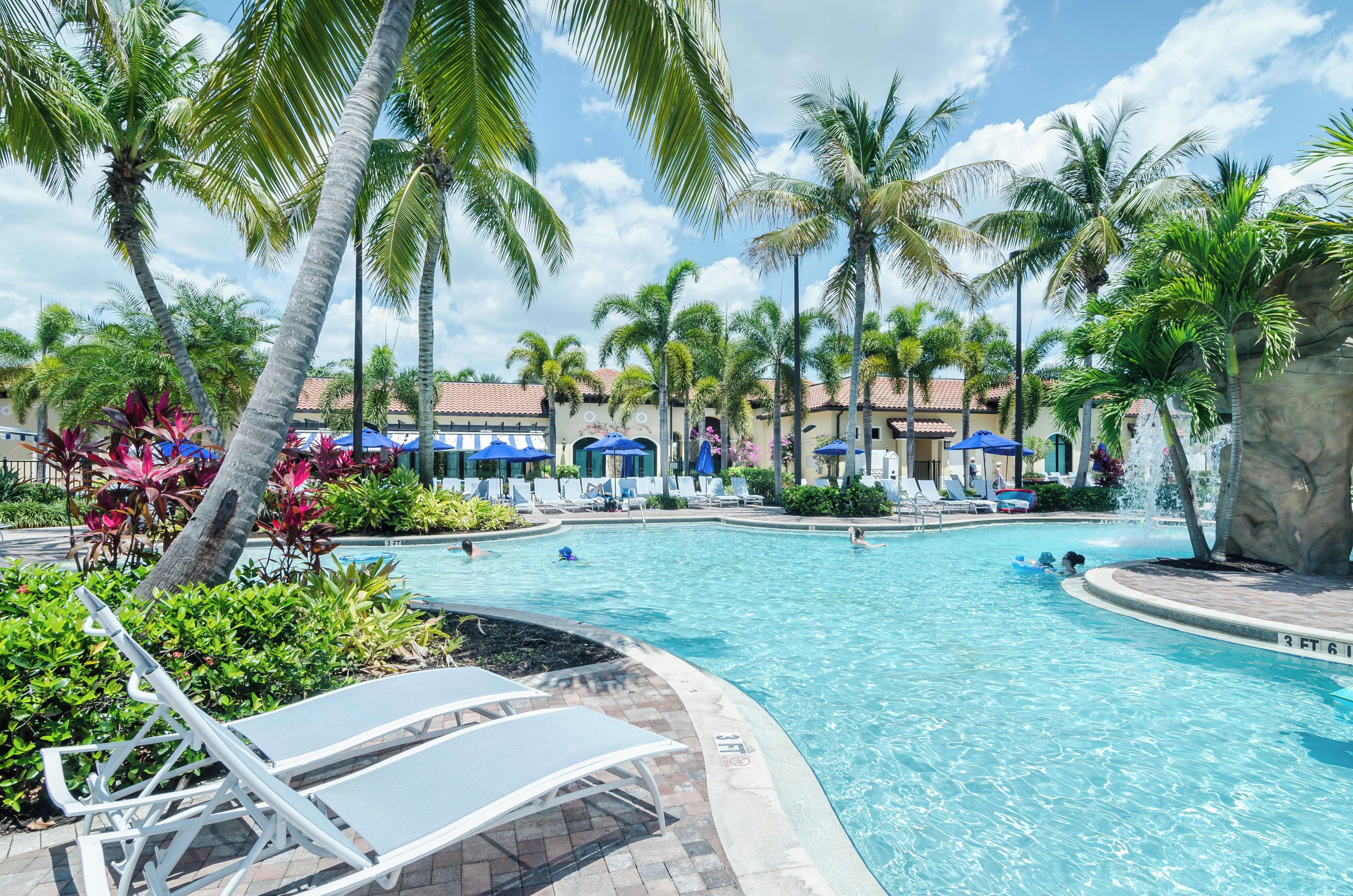 A swimming pool with lounge chairs and palm trees.