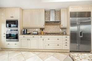A kitchen with white cabinets, stainless steel appliances, and a tiled backsplash.