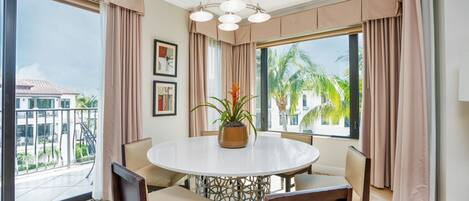 A dining area with a round table, chairs, and a potted plant.
