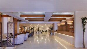 Un hall d’entrée spacieux comprenant un comptoir d’accueil, un espace détente et un design moderne au niveau du plafond.
