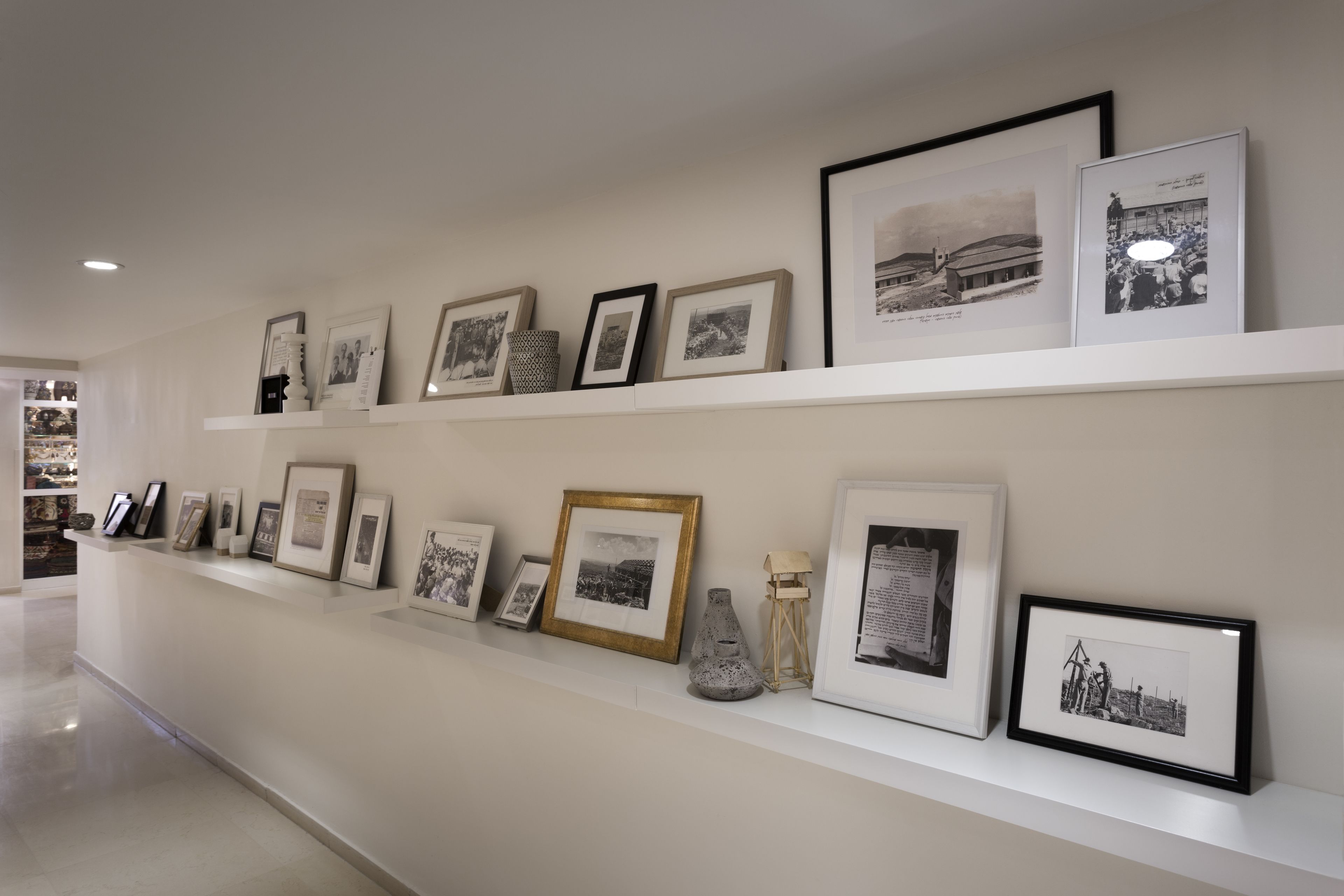 Uma parede de galeria com fotografias emolduradas e um vaso.