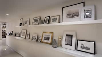 Uma parede de galeria com fotografias emolduradas e um vaso.