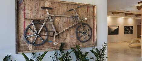 A large wooden artwork of a bicycle on a wall, surrounded by potted plants.