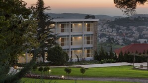 Un immeuble à plusieurs étages doté d’une architecture moderne, entouré de pelouses et d’arbres bien entretenus.