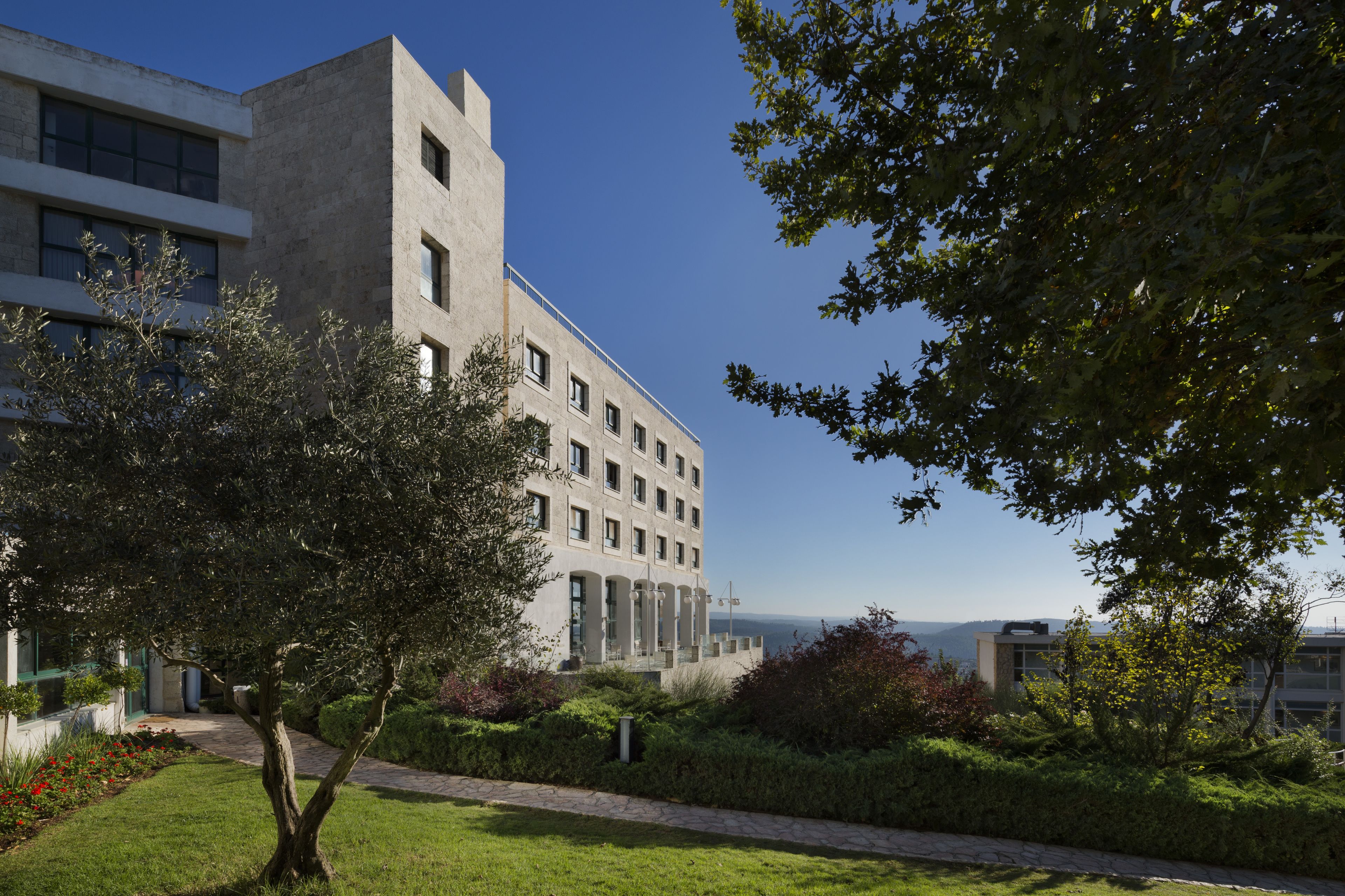 A modern building with a courtyard, surrounded by greenery and a clear view of the sky.