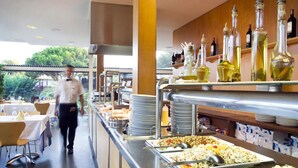 Zona de buffet con diferentes opciones de comida, un camarero caminando y una exhibición de vinos.