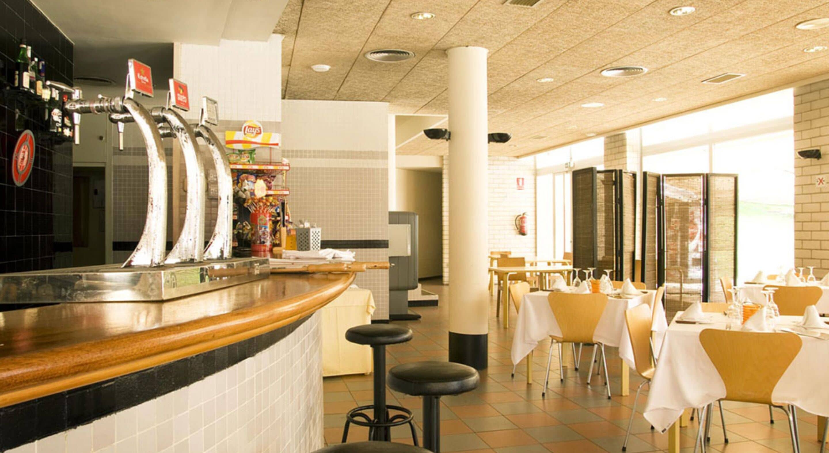 A restaurant with a bar area, multiple tables, and stools.