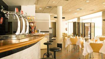 A restaurant with a bar area, multiple tables, and stools.