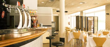 A restaurant with a bar area, multiple tables, and stools.