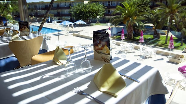 Mesa para dos personas dispuesta con un menú, copas de vino y cubiertos.