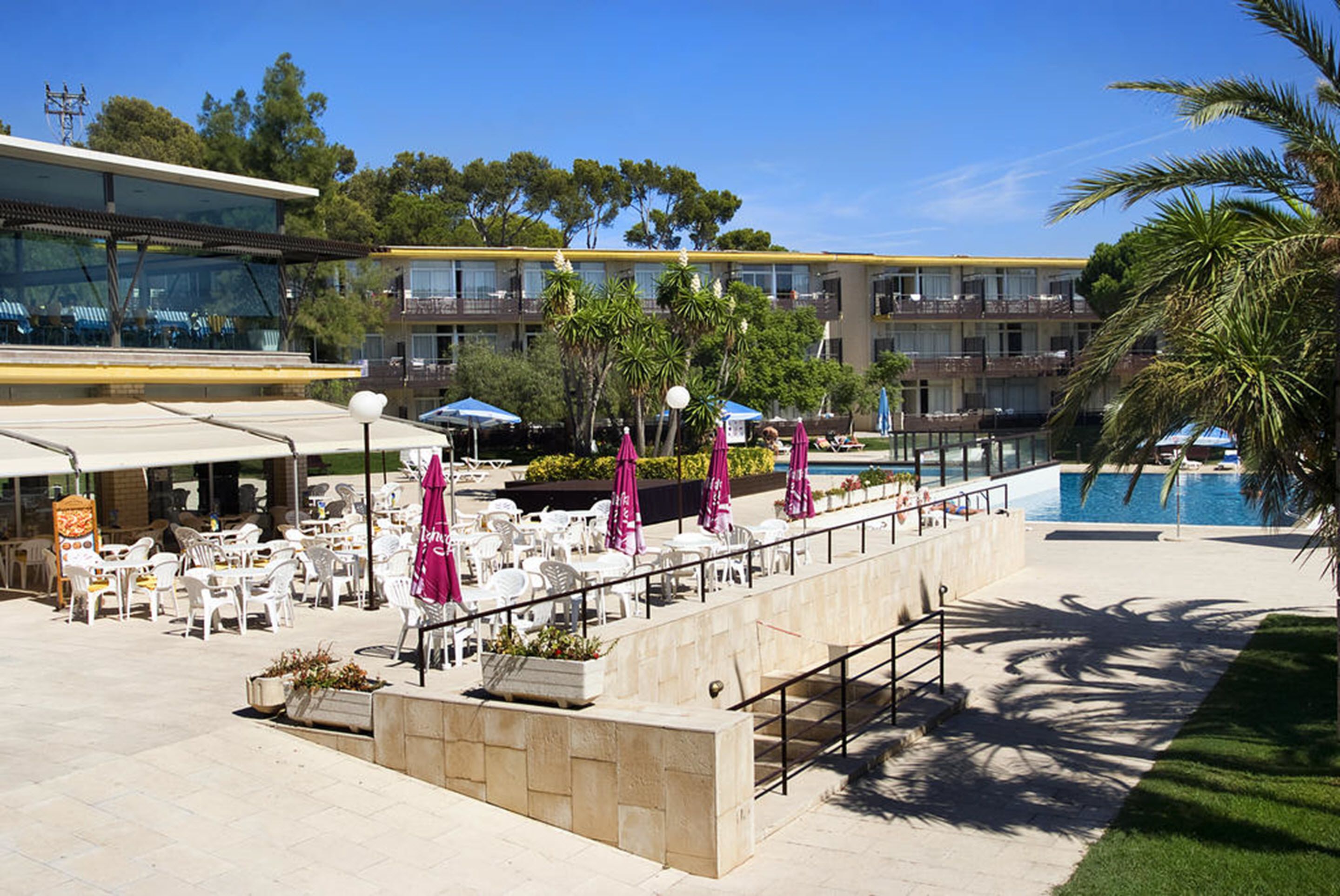 A poolside area with outdoor seating, a pool, and a building with multiple balconies.