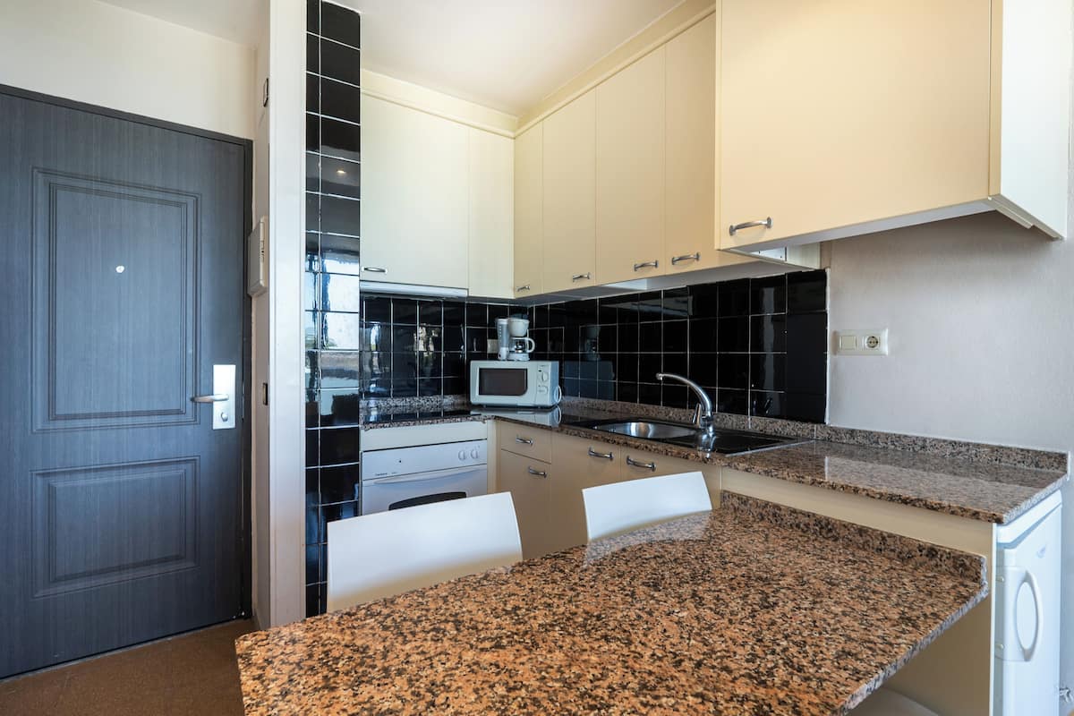 Una cocina moderna con armarios blancos, encimera de granito, microondas y fregadero.