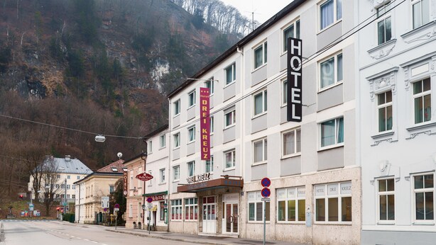 Un hotel con varios pisos, un cartel llamativo y montañas al fondo.