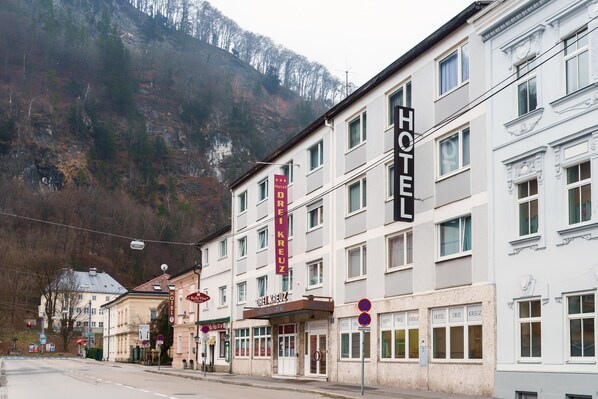 Un hotel con varios pisos, un cartel llamativo y montañas al fondo.
