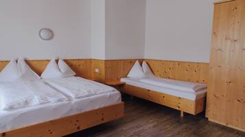 A room with two wooden beds, a wooden wardrobe, and a small table.