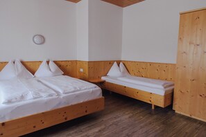 Een kamer met twee houten bedden, een kledingkast van hout en een klein tafeltje.