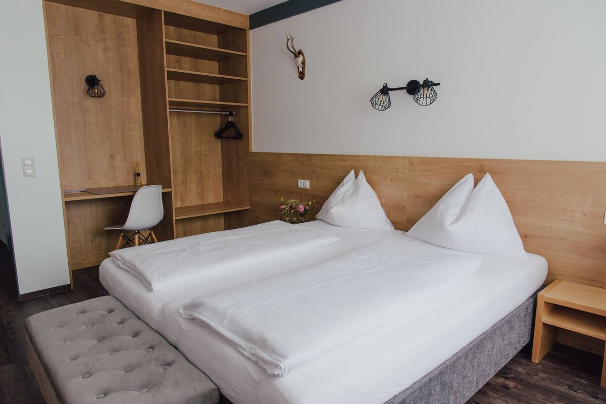Un dormitorio con una cama grande, cabecera de madera, un escritorio con silla y un armario.