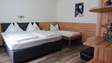Une chambre d’hôtel avec un grand lit, un lit plus petit, un bureau et une chaise.