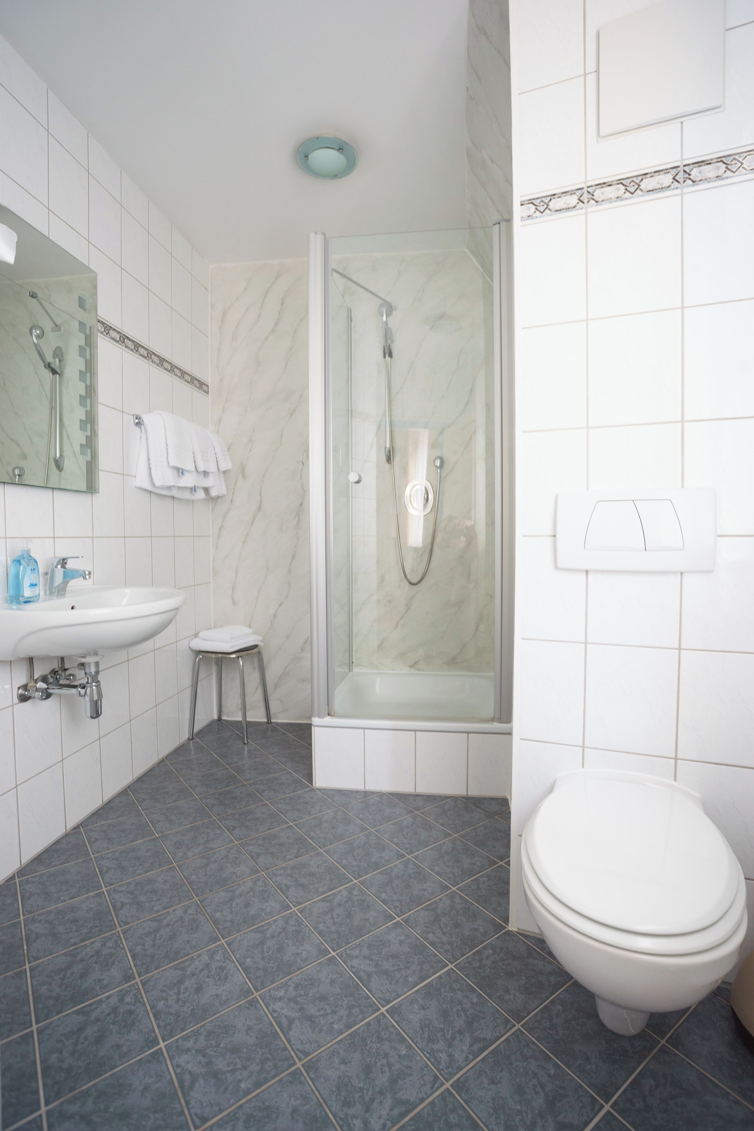 Un bagno moderno con doccia, servizi igienici, lavandino e specchio.