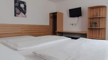 Een hotelkamer met twee bedden, een houten hoofdbord, een flatscreen televisie aan de muur en een houten plank met decoratieve objecten.