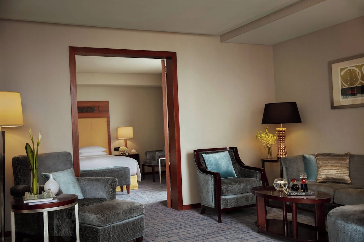 A hotel room with a bed, two armchairs, a sofa, a small table, and a lamp.