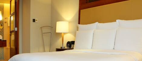 A hotel room with a large bed, a bedside table with a lamp, and a wooden headboard.