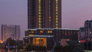 A high-rise hotel with multiple floors, a prominent 'R' on the side, and a well-lit facade.