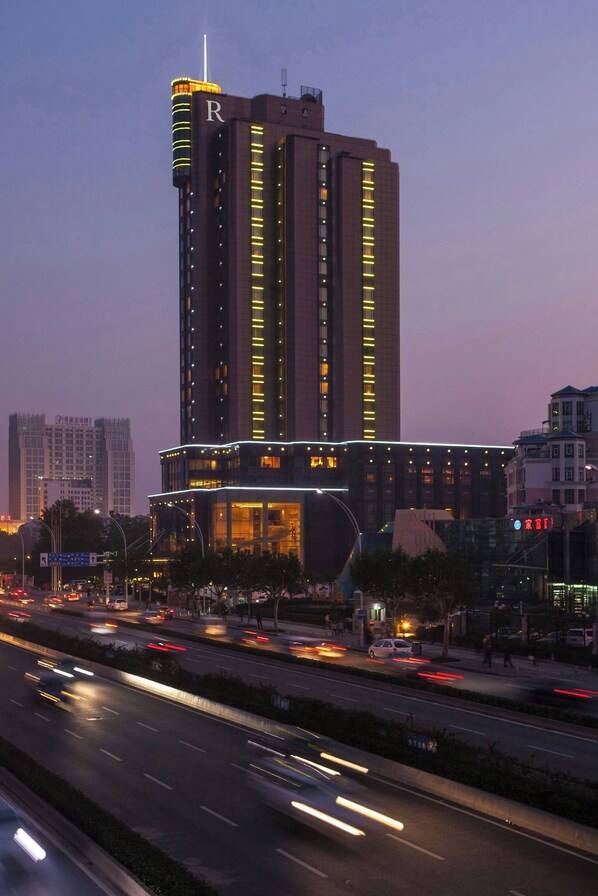 A high-rise hotel with multiple floors, a prominent 'R' on the side, and a well-lit facade.