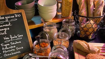A bakery display with jars of dried fruits, bowls, and loaves of bread.