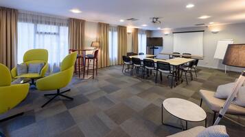 A conference room with a large table, multiple chairs, a projector, and a whiteboard.