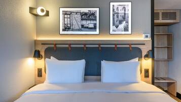 Una cama bien hecha con sábanas blancas, un cabecero con diseño texturizado y dos cuadros colgados en la pared arriba.