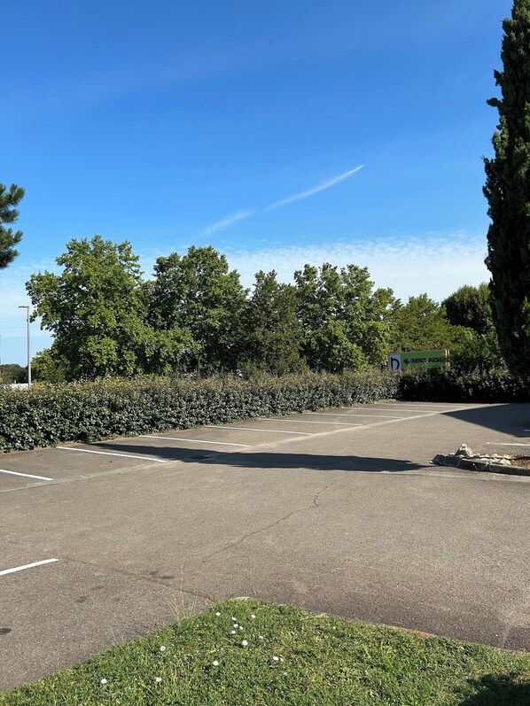 A parking lot with clear markings, surrounded by dense greenery and trees. - Campanile NATURE - Cahors (Cahors)