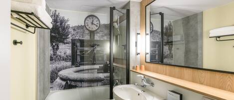 A bathroom with a bathtub, a sink, a mirror, and a clock on the wall.