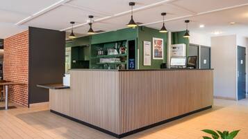 A reception area with a counter, pendant lights, a computer, and a menu board.
