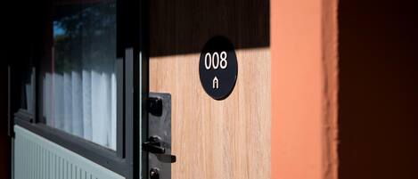 Une porte avec une plaque portant l’inscription « 008 » et un judas.