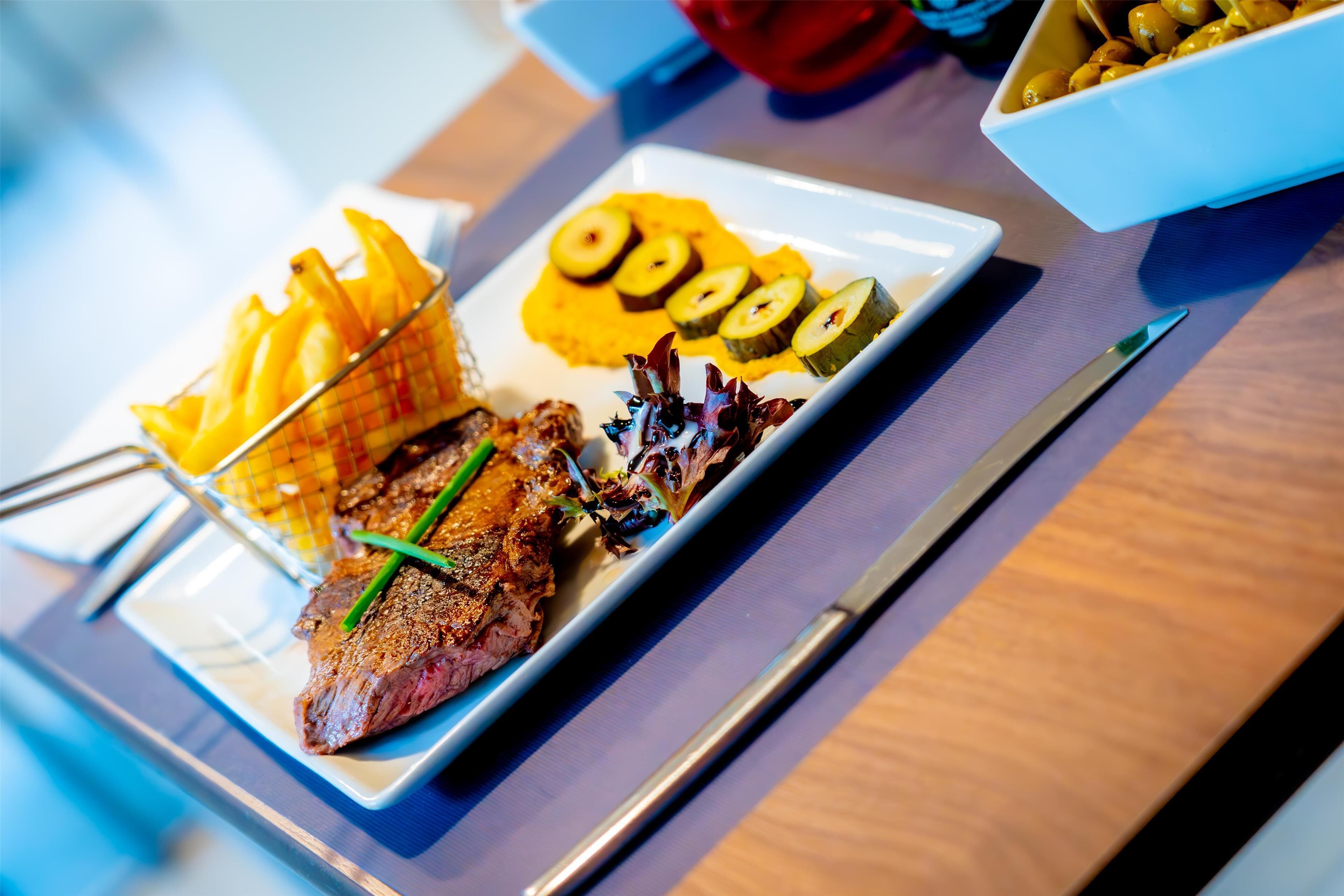 A plate of food with steak, fries, and vegetables.