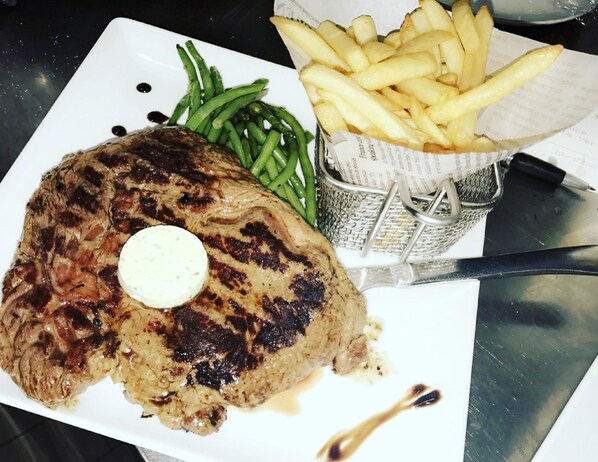 A steak with a pat of butter on top, served with green beans and French fries on a white plate. - Campanile Saint Avold (Saint-Avold)