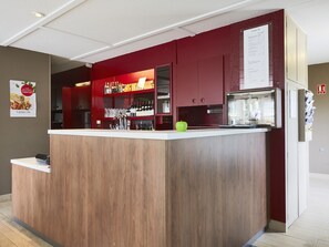 A bar area with a wooden counter, red cabinets, and a menu board. - Campanile Saint Avold (Saint-Avold)