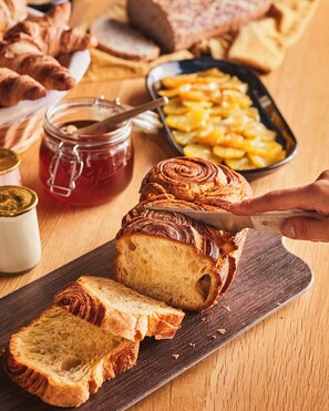 A loaf of bread being sliced on a wooden cutting board with a knife. - Campanile Saint Avold (Saint-Avold)