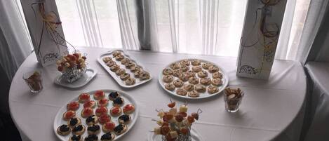 A table with various food items, including canapés and pastries, arranged on a white tablecloth.