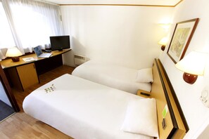 A hotel room with a bed, a desk with a laptop, a television, and two bedside lamps. - Campanile Saint Avold (Saint-Avold)