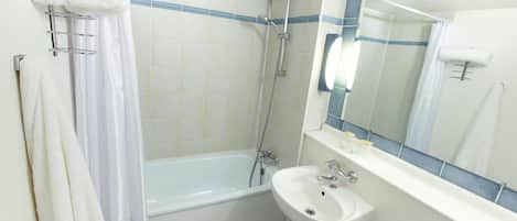 A bathroom with a bathtub, a sink, and a mirror.