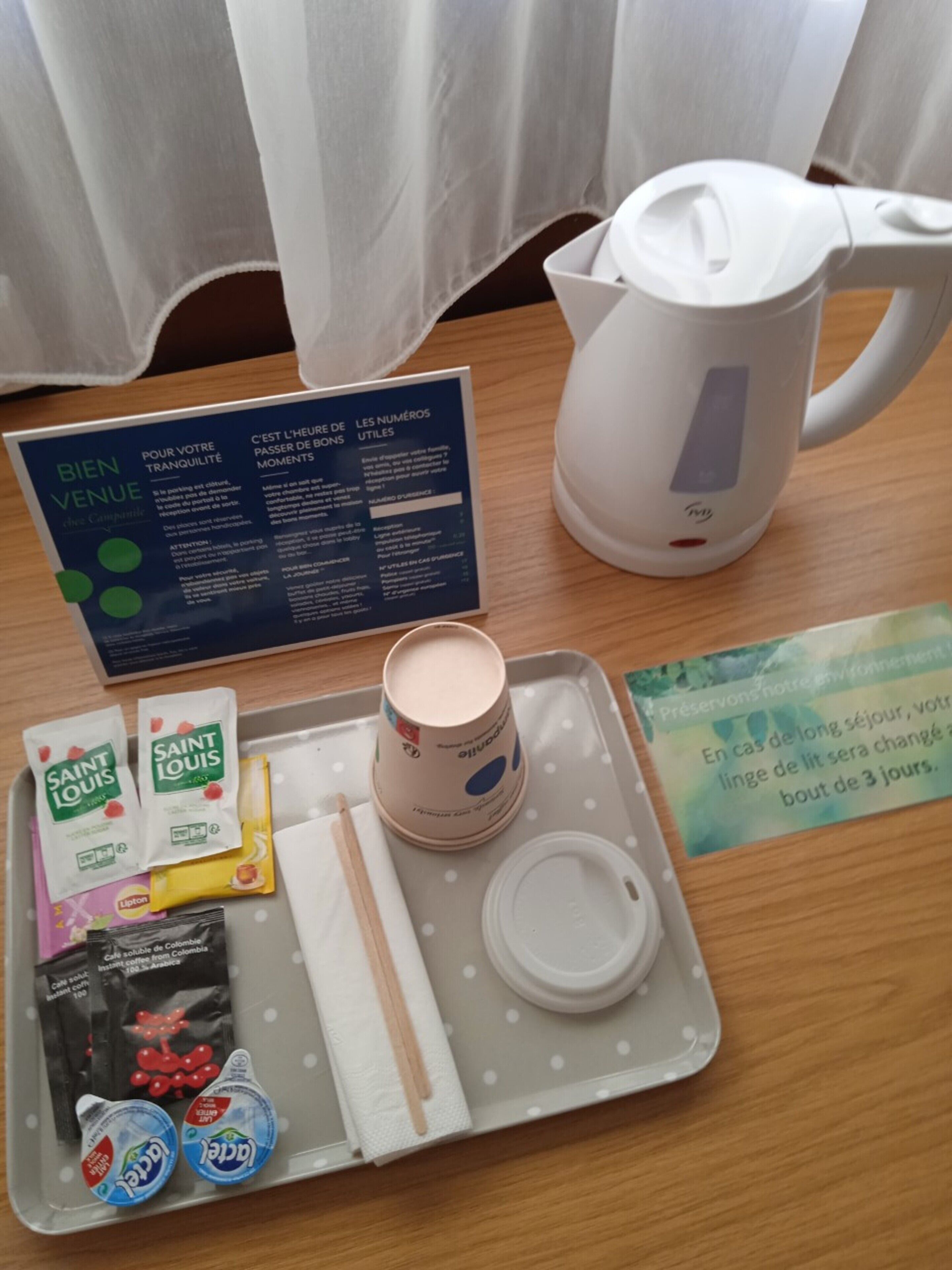 Una bandeja con una cafetera, servilletas, un cartel y diversos artículos de aseo.