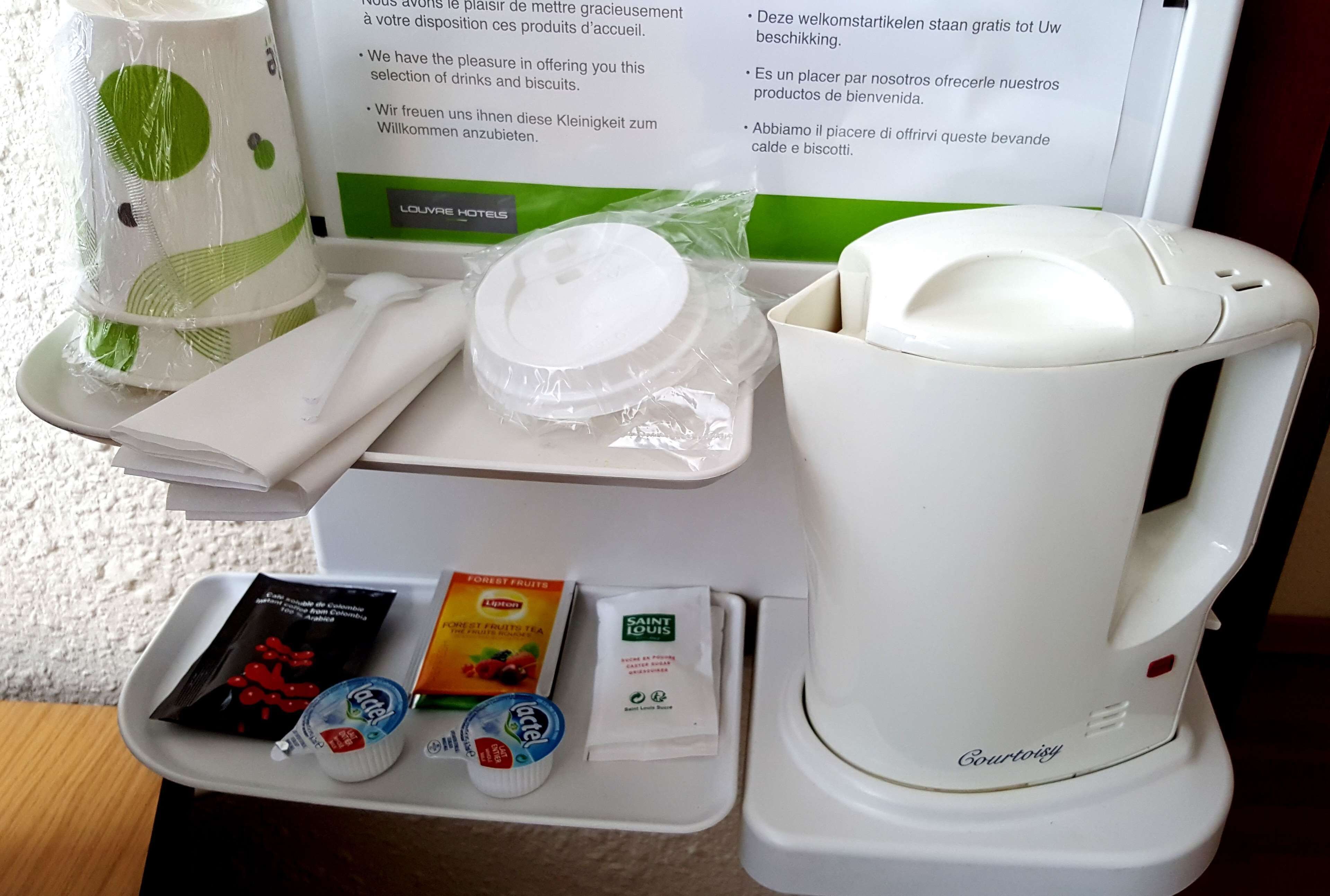 Ein Frühstücksangebot im Hotelzimmer, darunter eine Kaffeemaschine, ein Tablett mit Speisen und eine Speisekarte.
