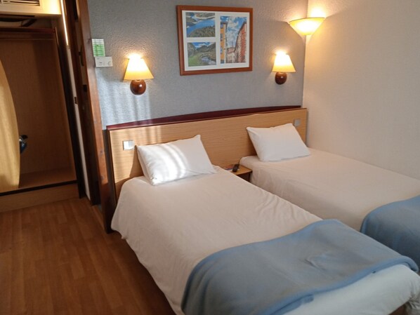 A hotel room with two beds, wooden headboards, and wall-mounted lamps. - Hotel Campanile Aurillac (Aurillac)