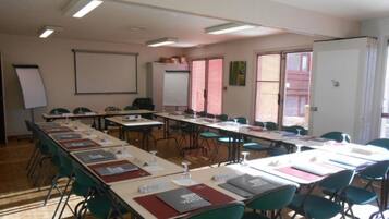 Un aula con filas de escritorios, sillas, una pantalla de proyector y una pizarra.