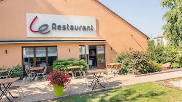 A restaurant with outdoor seating and a large sign.