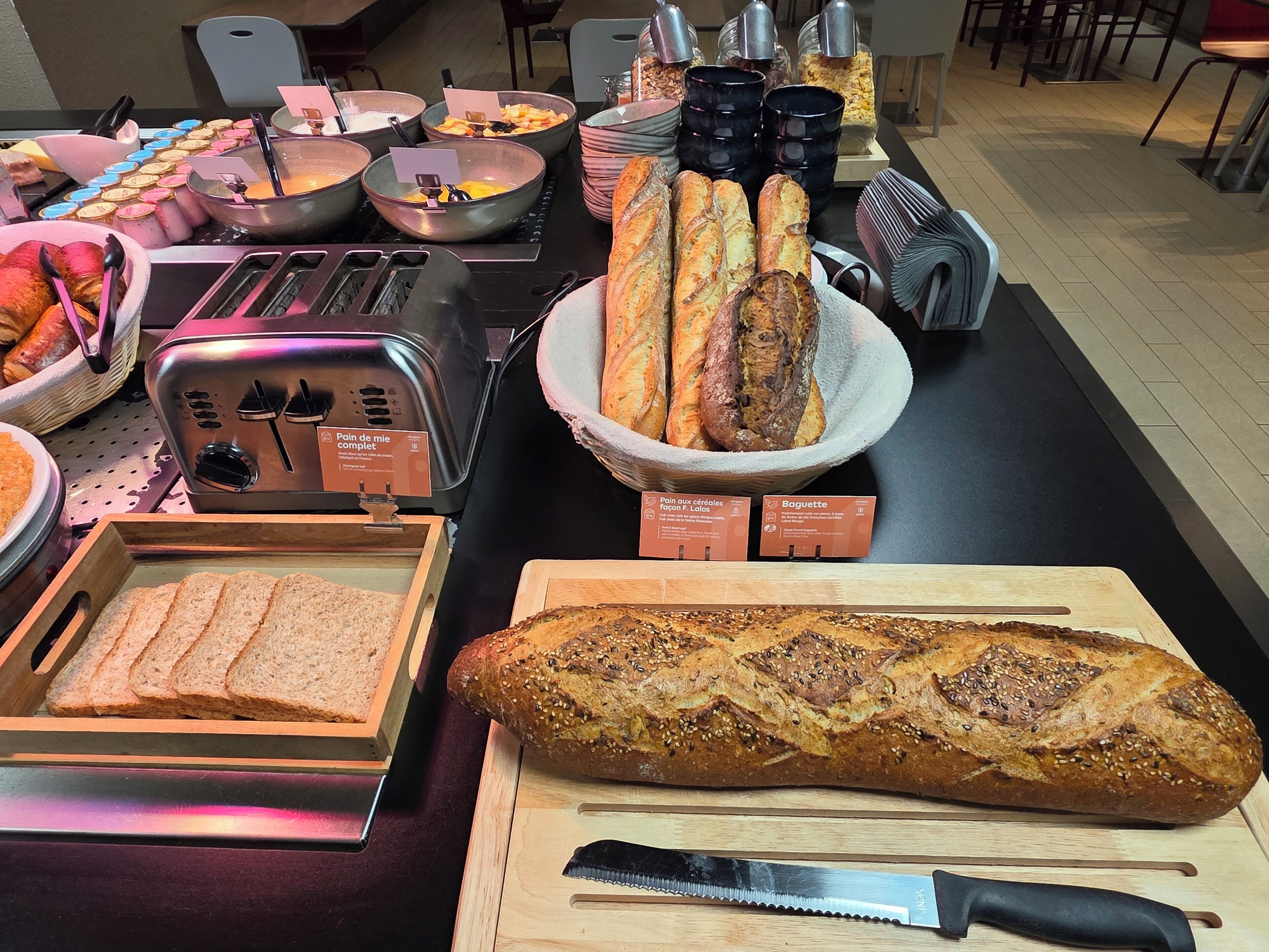 A buffet table with various breads, including baguettes and sliced bread, and a toaster.