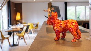 A modern dining area with a decorative ceramic bull sculpture on a table, yellow chairs, and a lamp in the background. - Kyriad Digne les Bains (Digne-les-Bains)