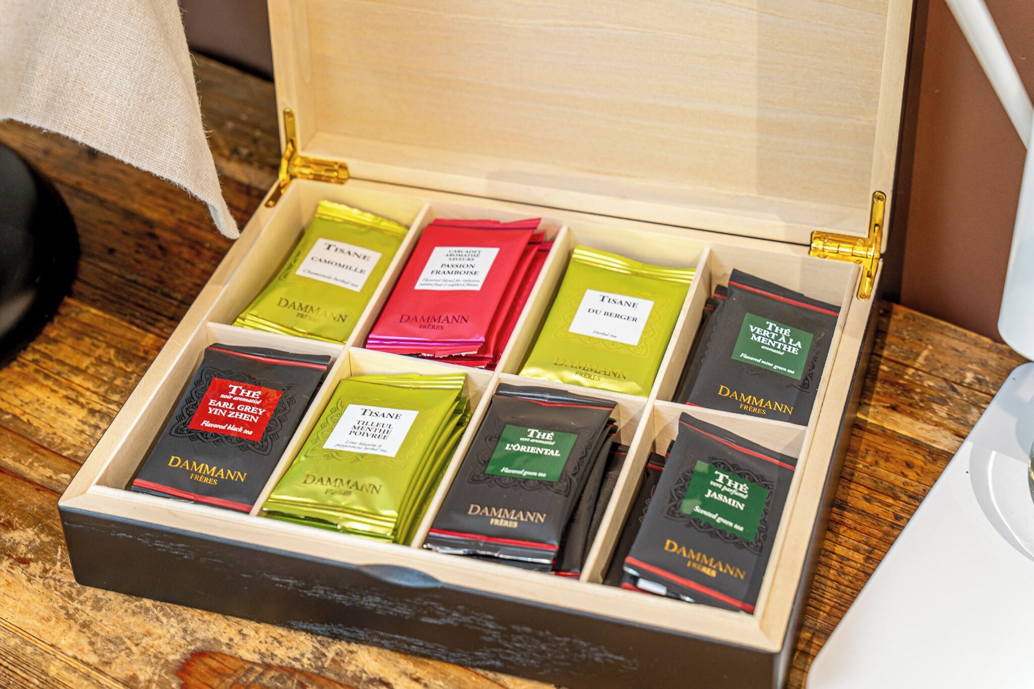 A wooden box with compartments containing various tea boxes labeled 'DAMMANN FRANKE'.